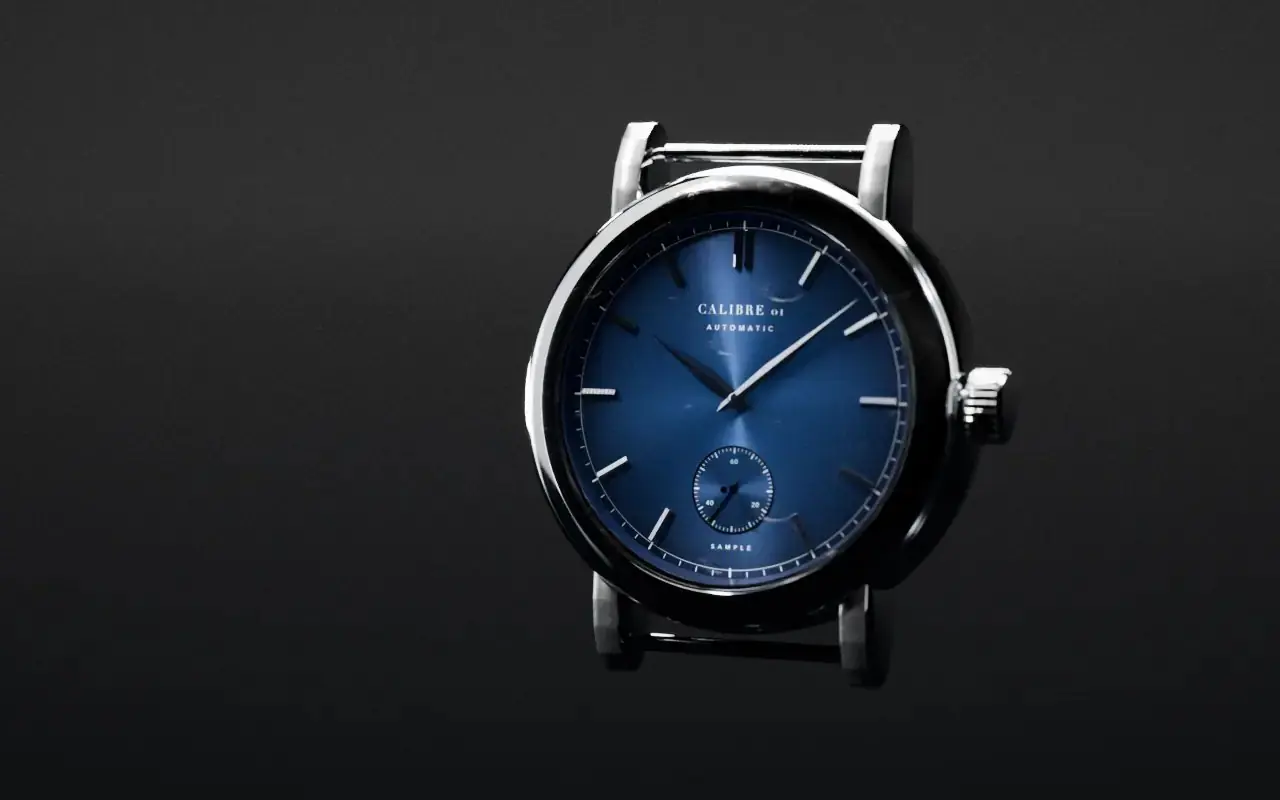 Calibre 01, a sample automatic watch with a blue sunburst dial and a polished steel case, lit in a black studio