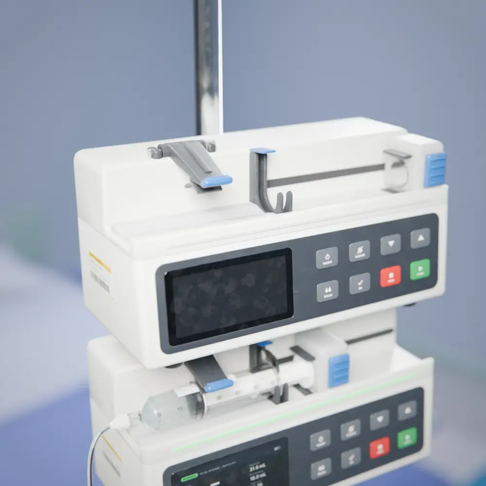 The invented syringe pump on its IV pole, switched off, with the barrel clamp down and no syringe loaded