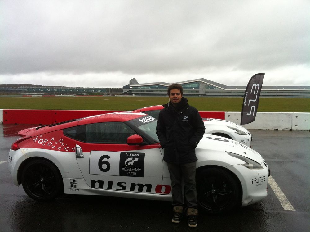 Mo beside a GT Academy Nissan race car at Silverstone, with the circuit behind.