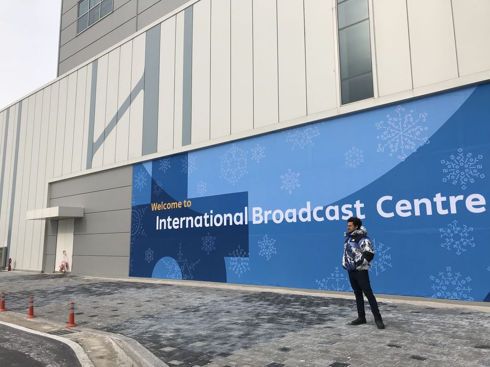 Mo outside a long wall printed Welcome to International Broadcast Centre.
